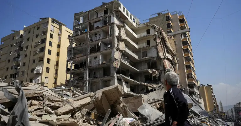 বৈরুতের দক্ষিণ উপশহরে ইসরাইলি হামলায় ক্ষতিগ্রস্ত এক ভবনের পাশে দাঁড়িয়ে থাকা এক ব্যক্তি